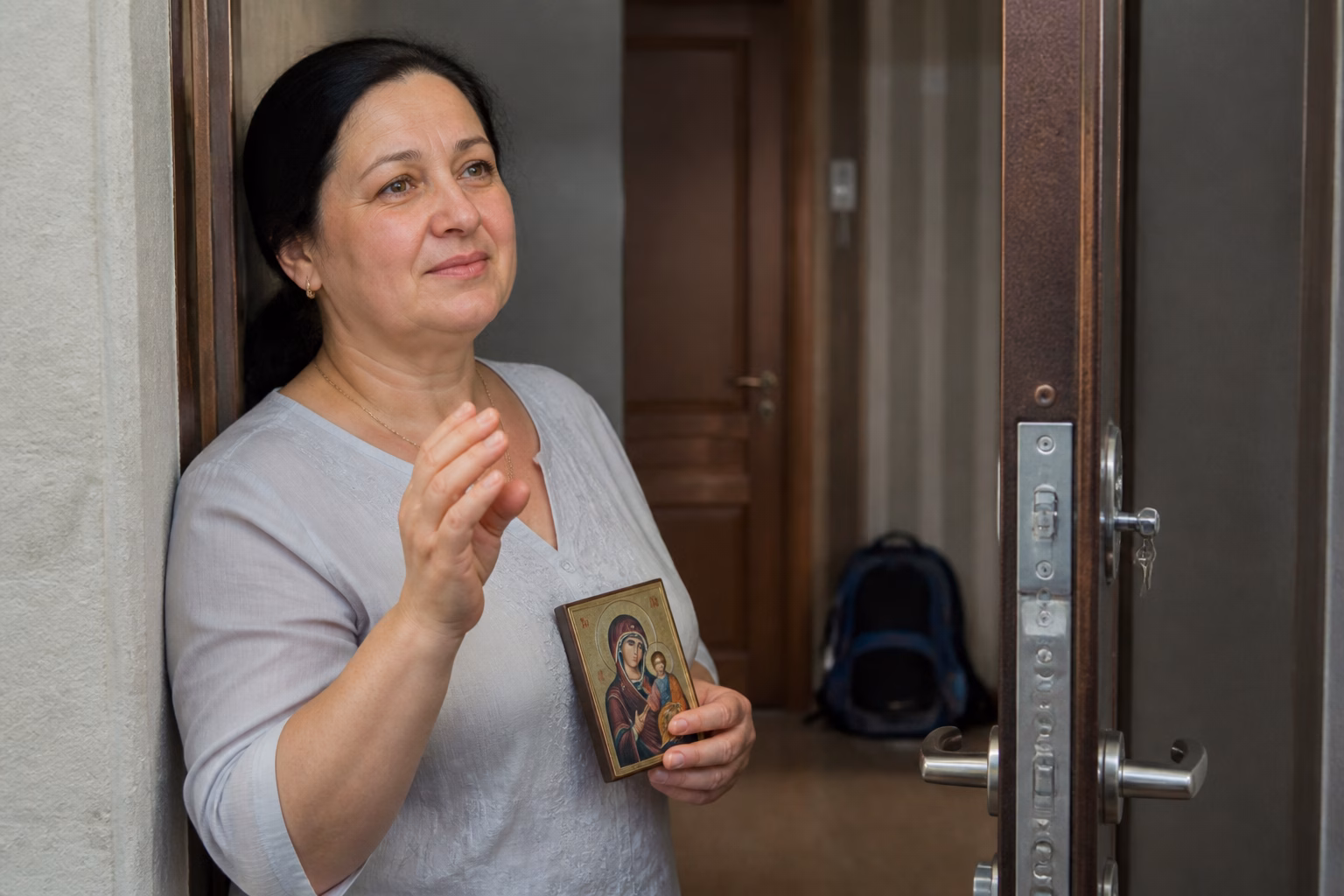 Мати молиться з іконою біля дверей, проводжаючи дитину на іспит