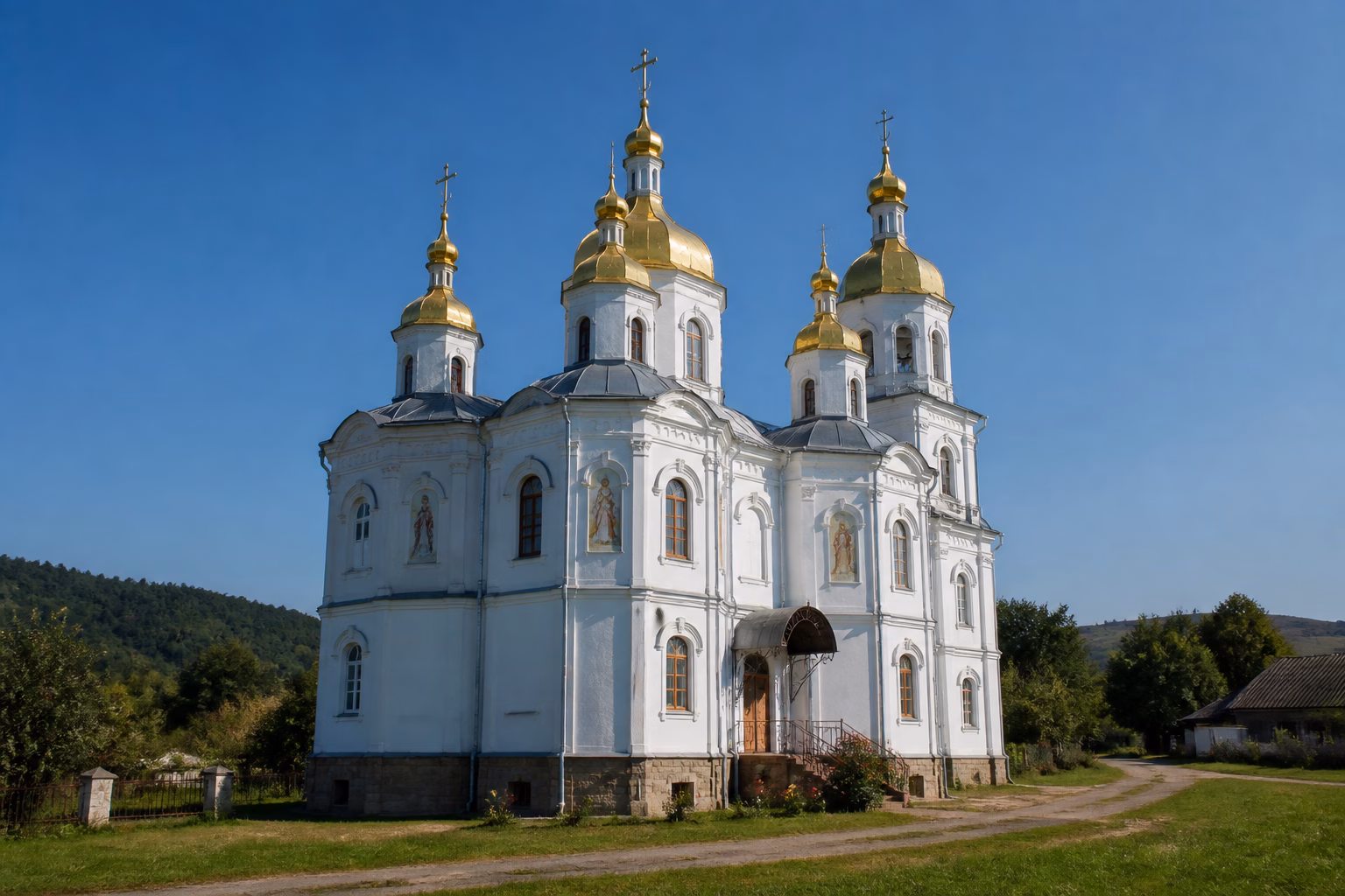 Українська православна церква з золотими куполами на тлі сільського пейзажу